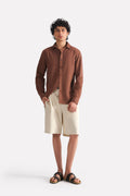 Beige linen drawstring shorts, worn by a model, by SOLA Pakistan.
