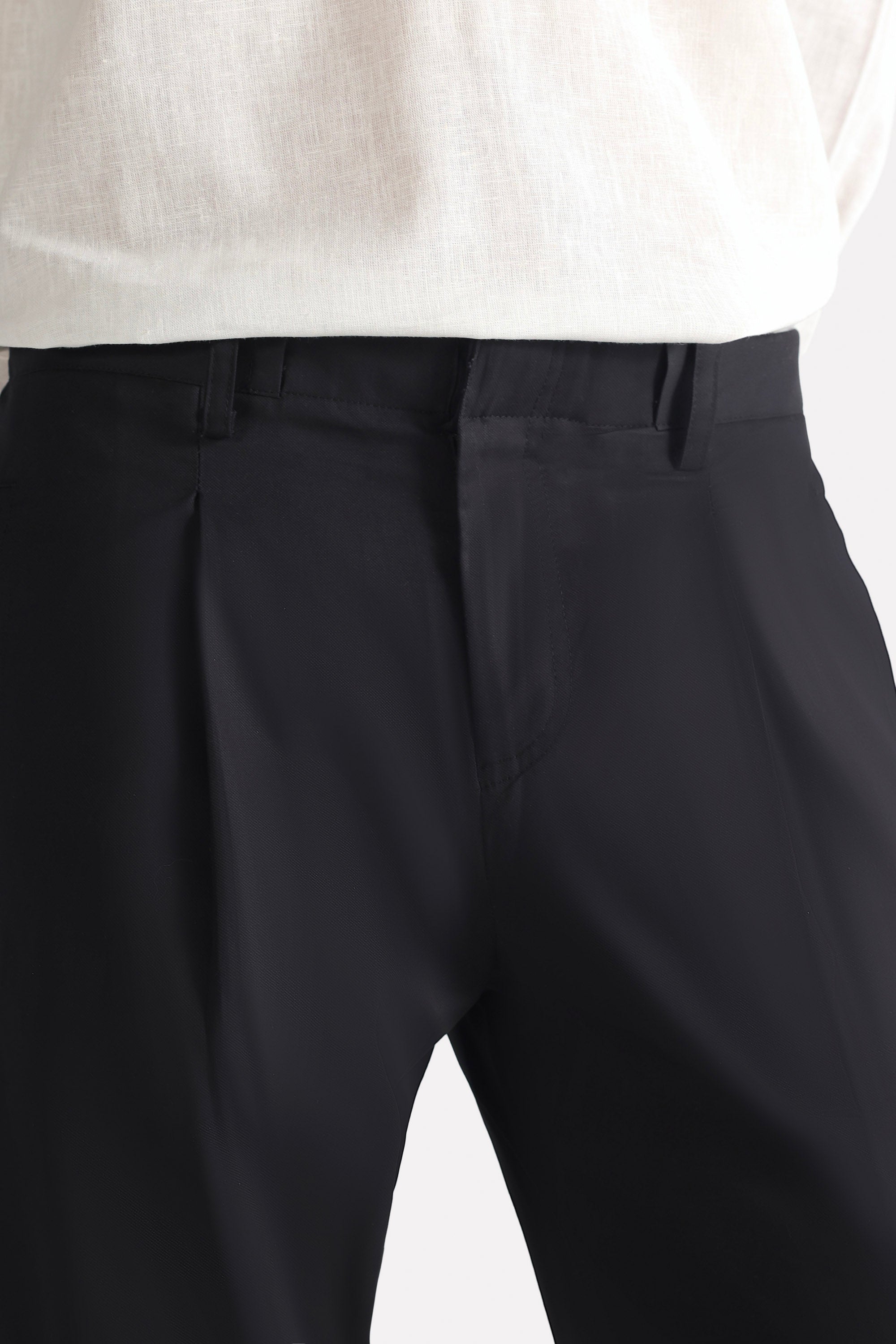 Close-up detail on the black barrel-leg pleated trouser, by SOLA Pakistan.