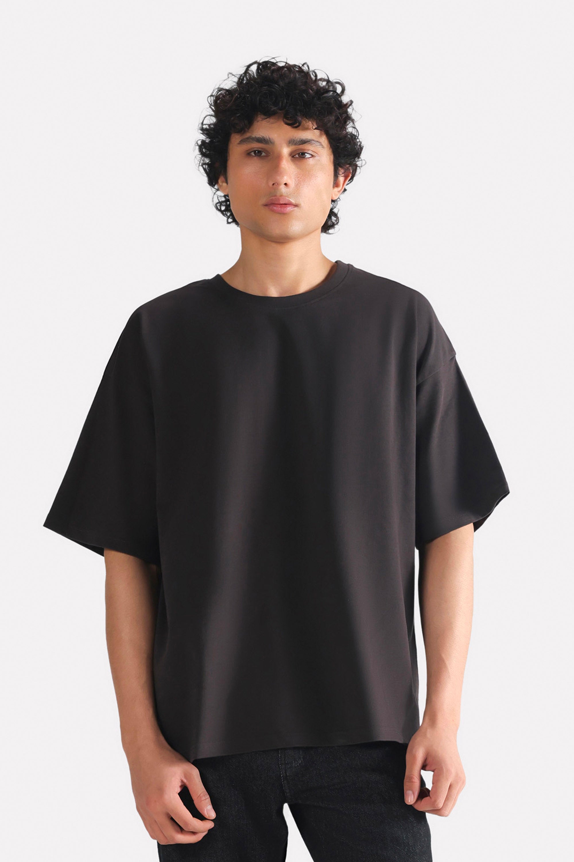 Black drop shoulder cotton t-shirt, worn by a model, by SOLA Pakistan.