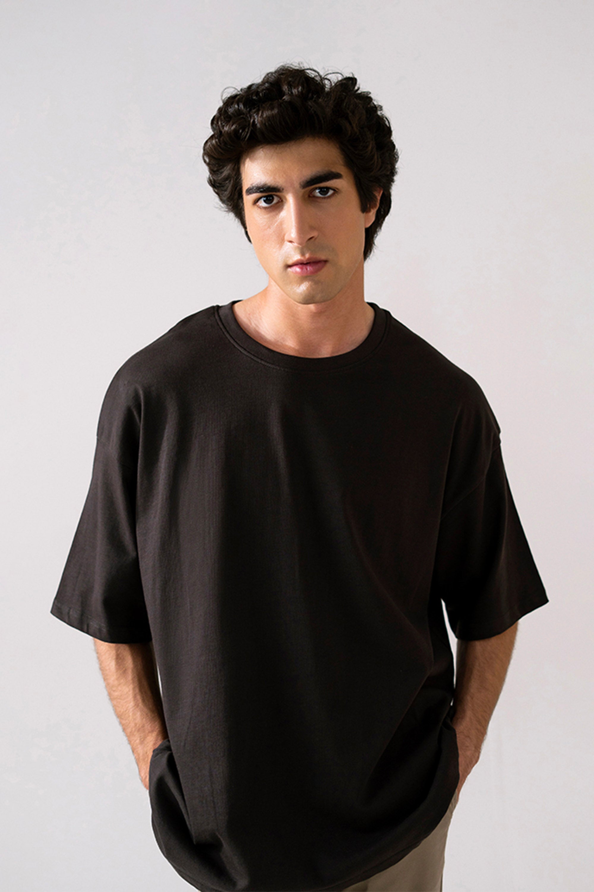 Black heavy weight cropped t-shirt in cotton, worn by a model, by SOLA Pakistan.