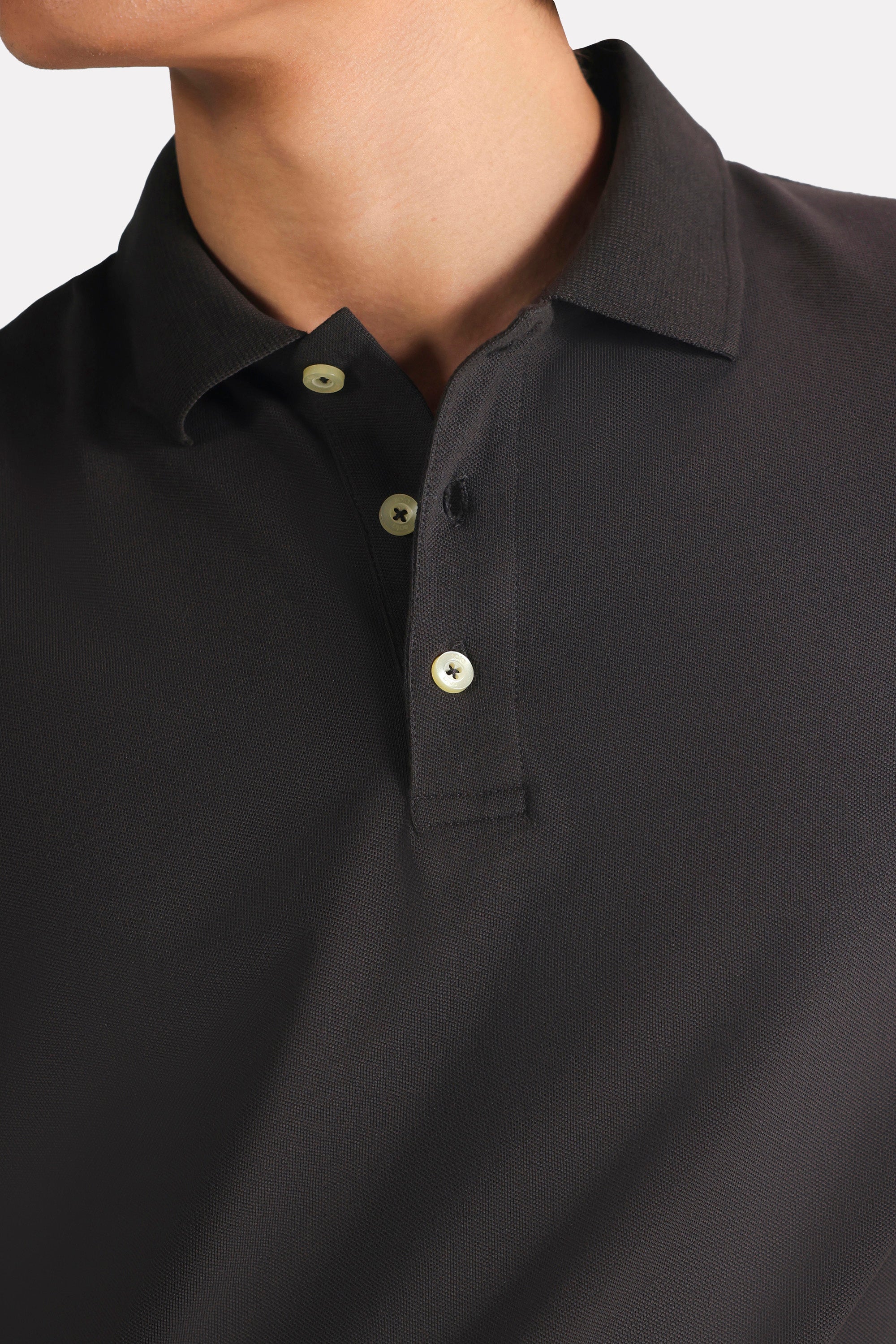 Close-up detail on the black micro-textured cotton pique polo, by SOLA Pakistan.