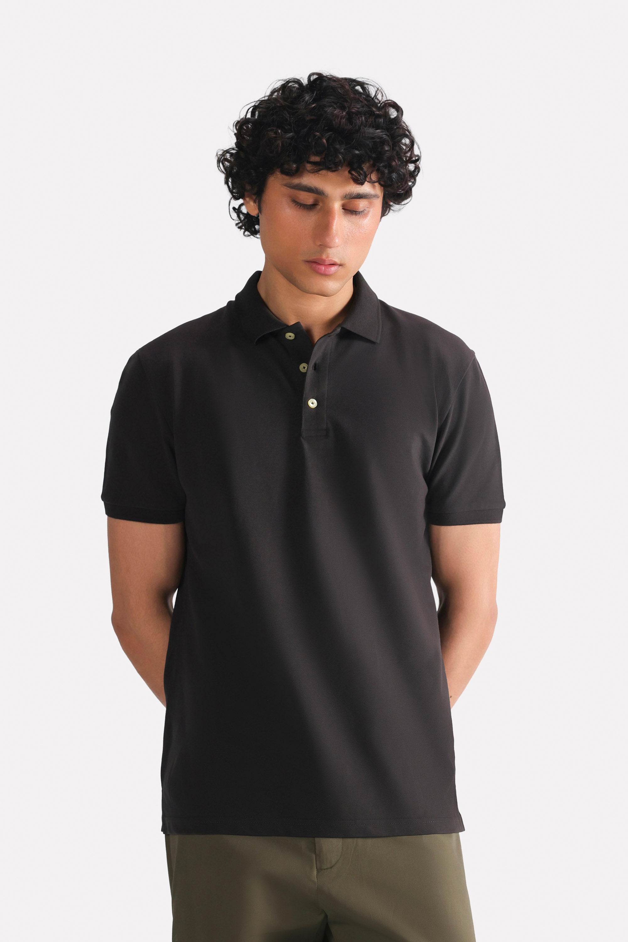 Black micro-textured cotton pique polo, worn by a model, by SOLA Pakistan.