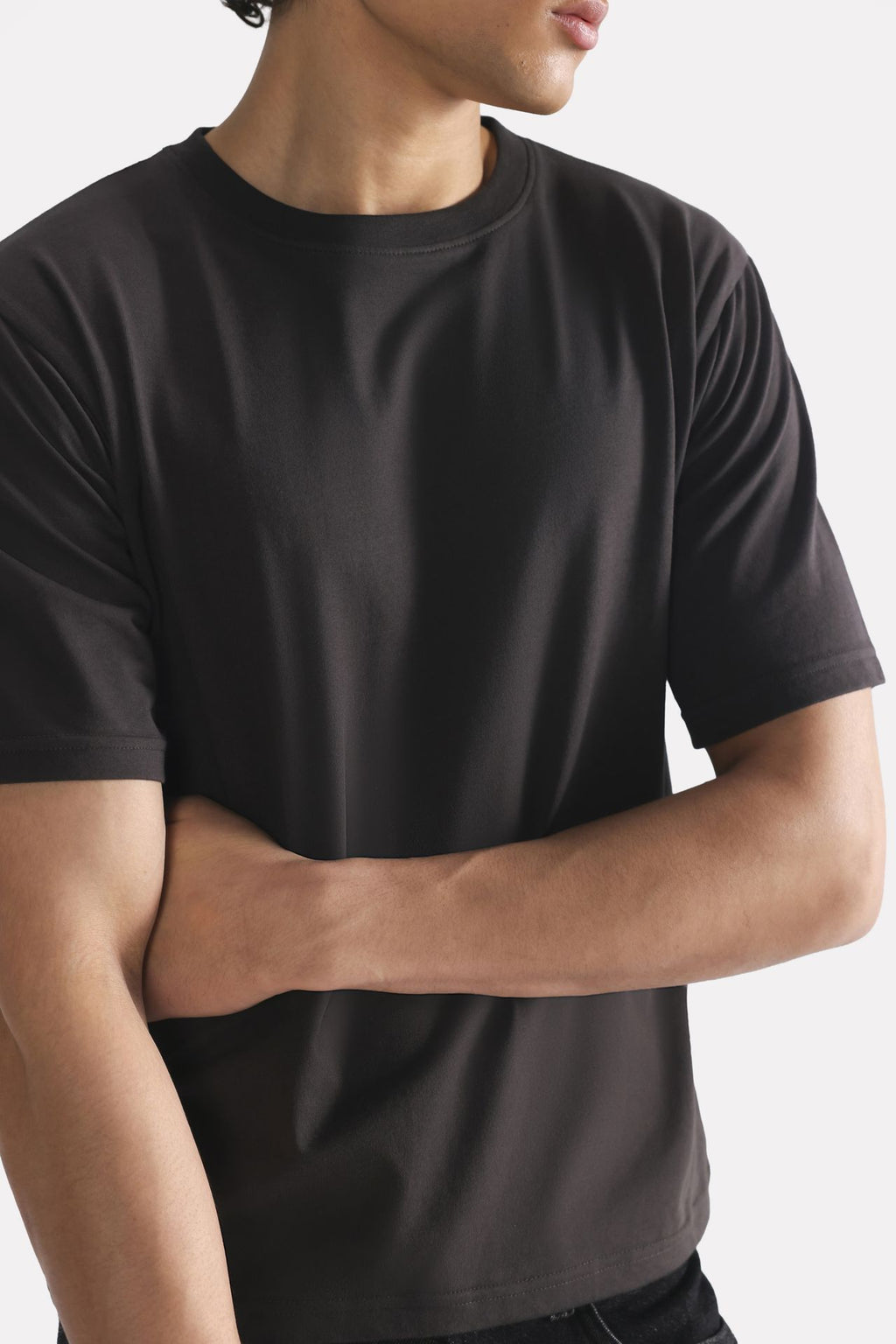 Black regular fit crew neck t-shirt shown in a styled fit, by SOLA Pakistan.