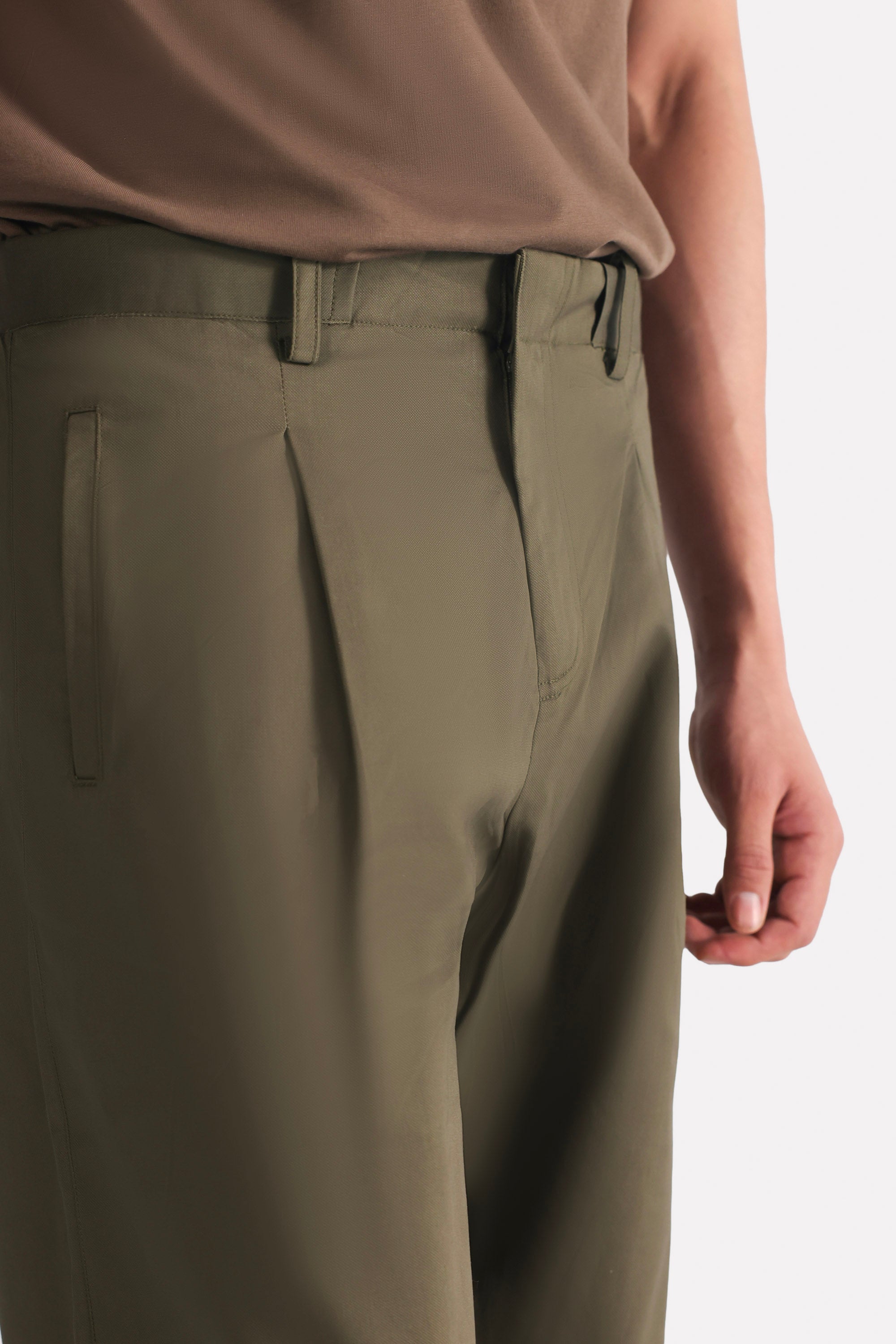 Close-up detail on the dark olive barrel-leg pleated trouser, by SOLA Pakistan.