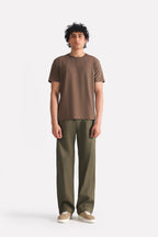 Dark olive barrel-leg pleated trouser in cotton, worn by a model, by SOLA Pakistan.