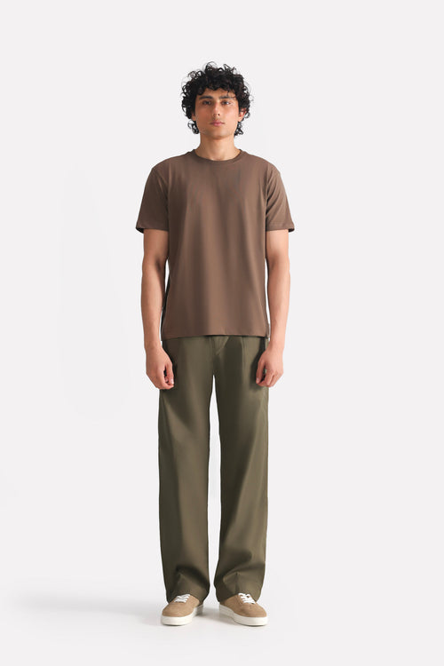 Dark olive barrel-leg pleated trouser in cotton, worn by a model, by SOLA Pakistan.