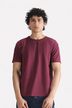 Dark red (burgundy) regular fit crew neck t-shirt in cotton, worn by a model, by SOLA Pakistan.