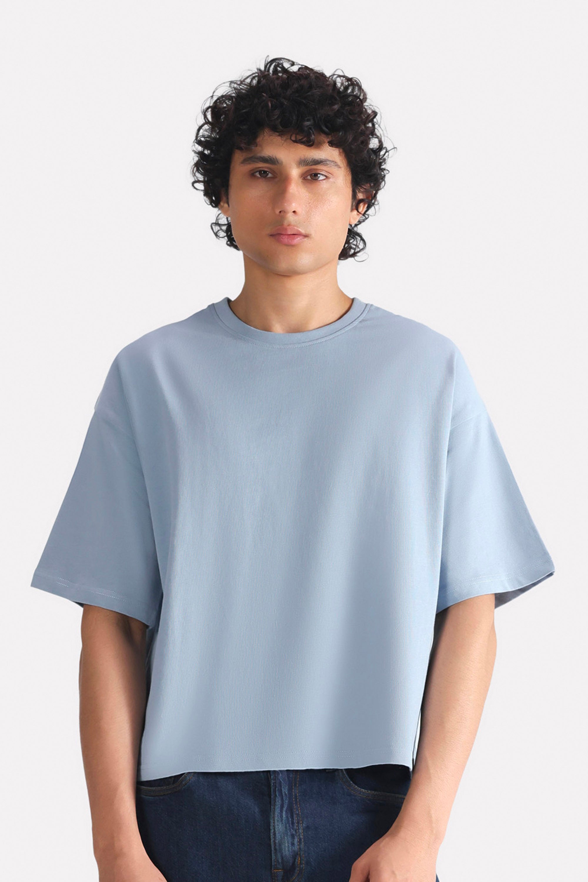 Faded blue (faded denim) drop shoulder cotton t-shirt, worn by a model, by SOLA Pakistan.