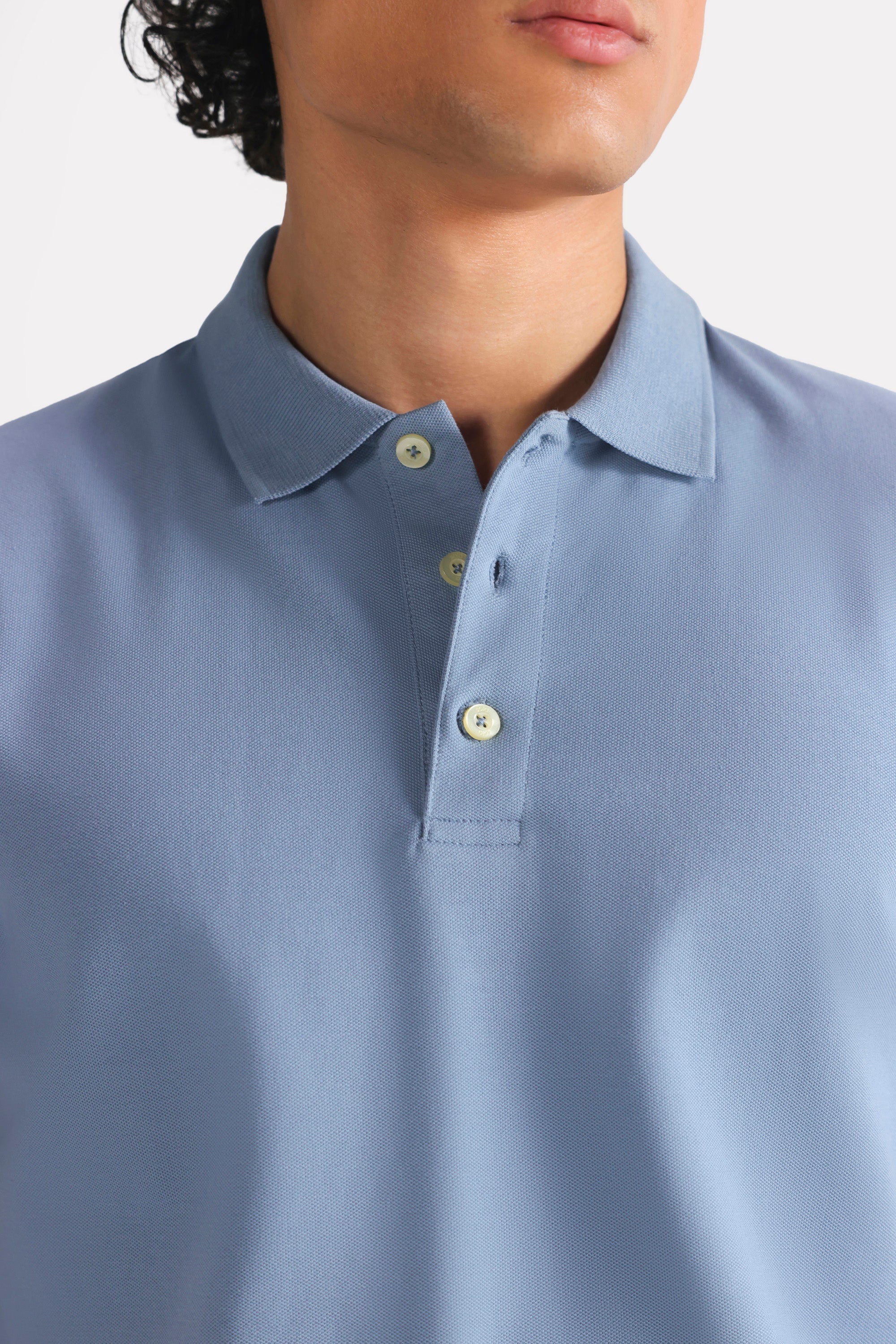 Close-up detail on the faded blue (faded denim) micro-textured cotton pique polo, by SOLA Pakistan.