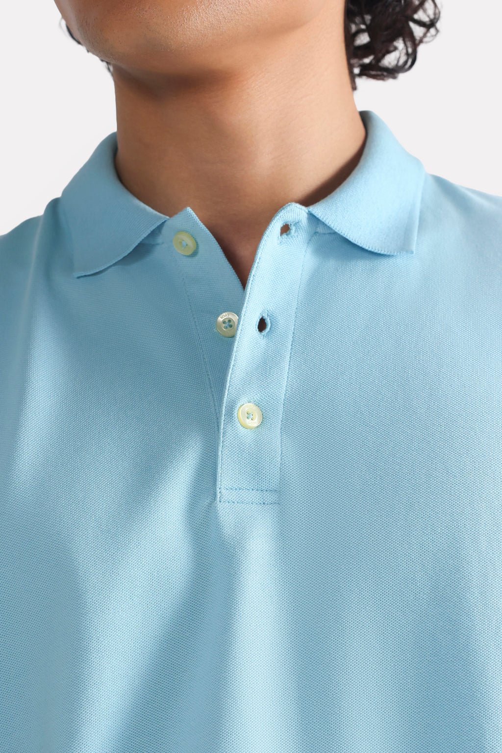 Close-up detail on the light blue micro-textured cotton pique polo, by SOLA Pakistan.