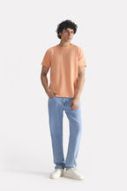 Peach (apricot) regular fit crew neck t-shirt shown in a styled fit, by SOLA Pakistan.