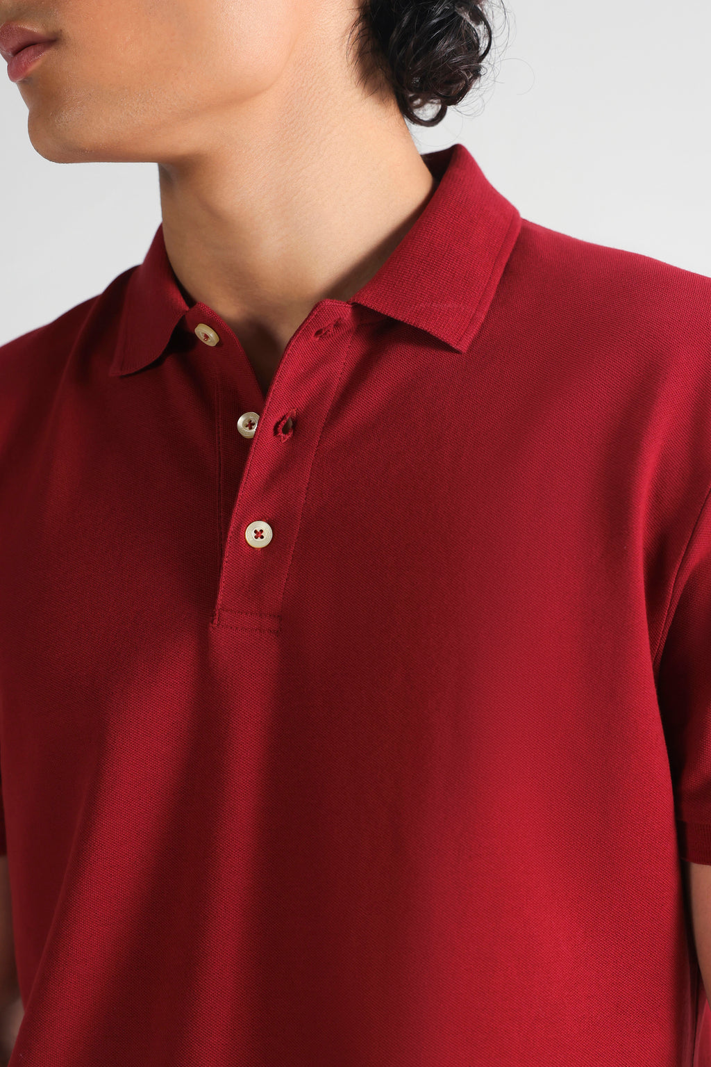 Close-up detail on the red (red riding hood) micro-textured cotton pique polo, by SOLA Pakistan.