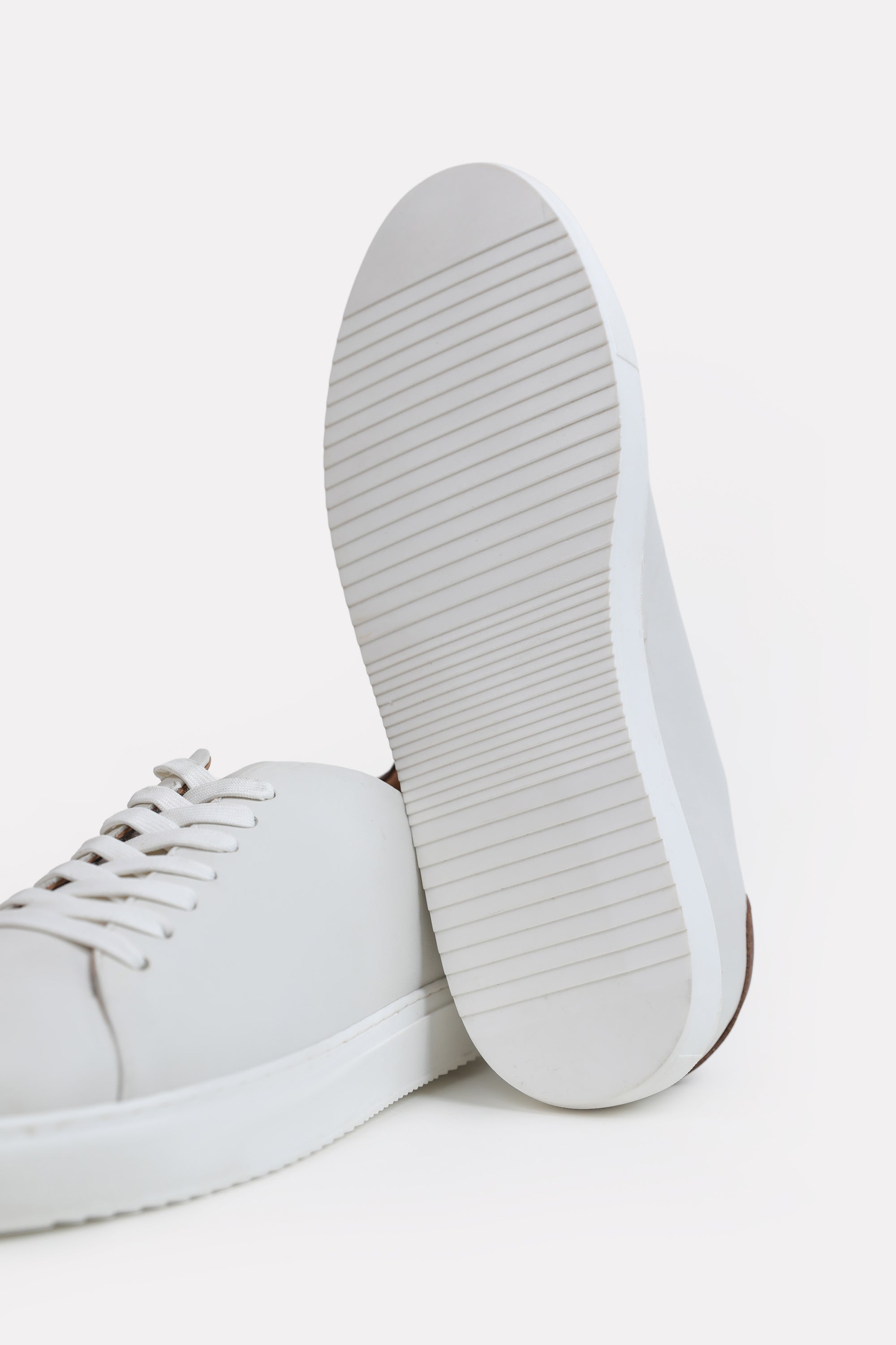 Close-up detail on the white leather trainers-detailed heel, by SOLA Pakistan.
