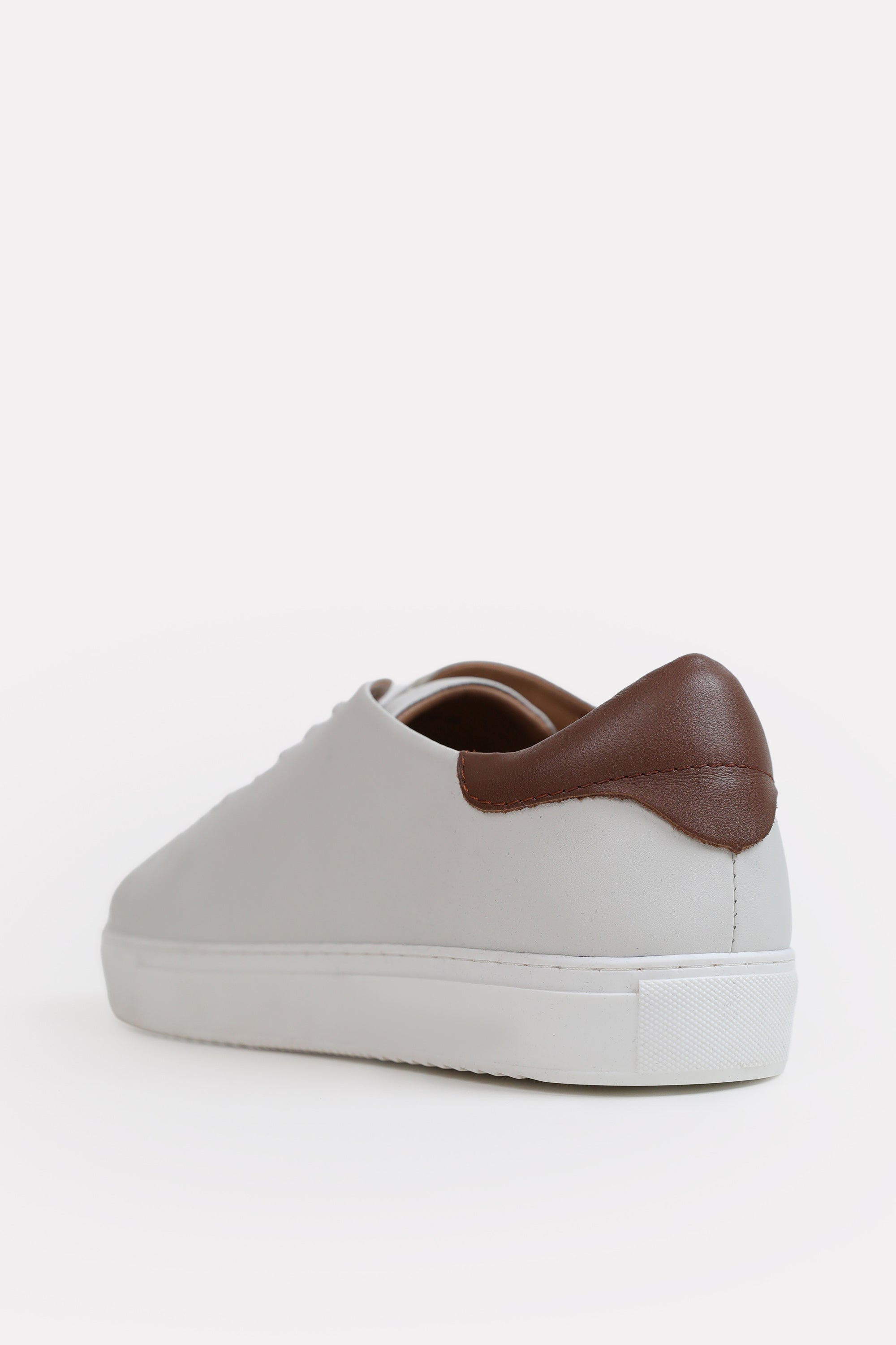 Flat lay of the white leather trainers-detailed heel, by SOLA Pakistan.