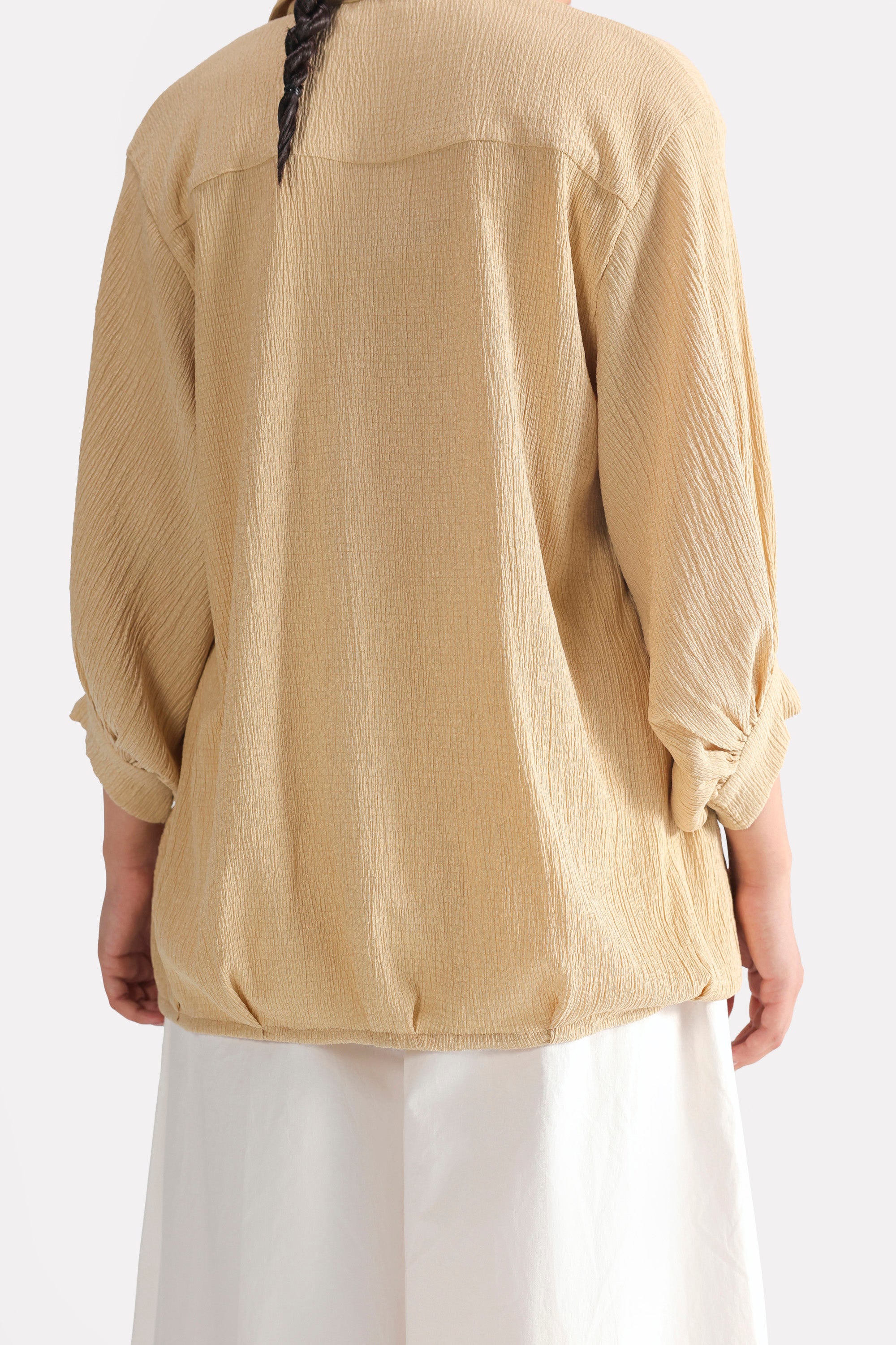 Flat lay of the beige pleated hem woven top, by SOLA Pakistan.