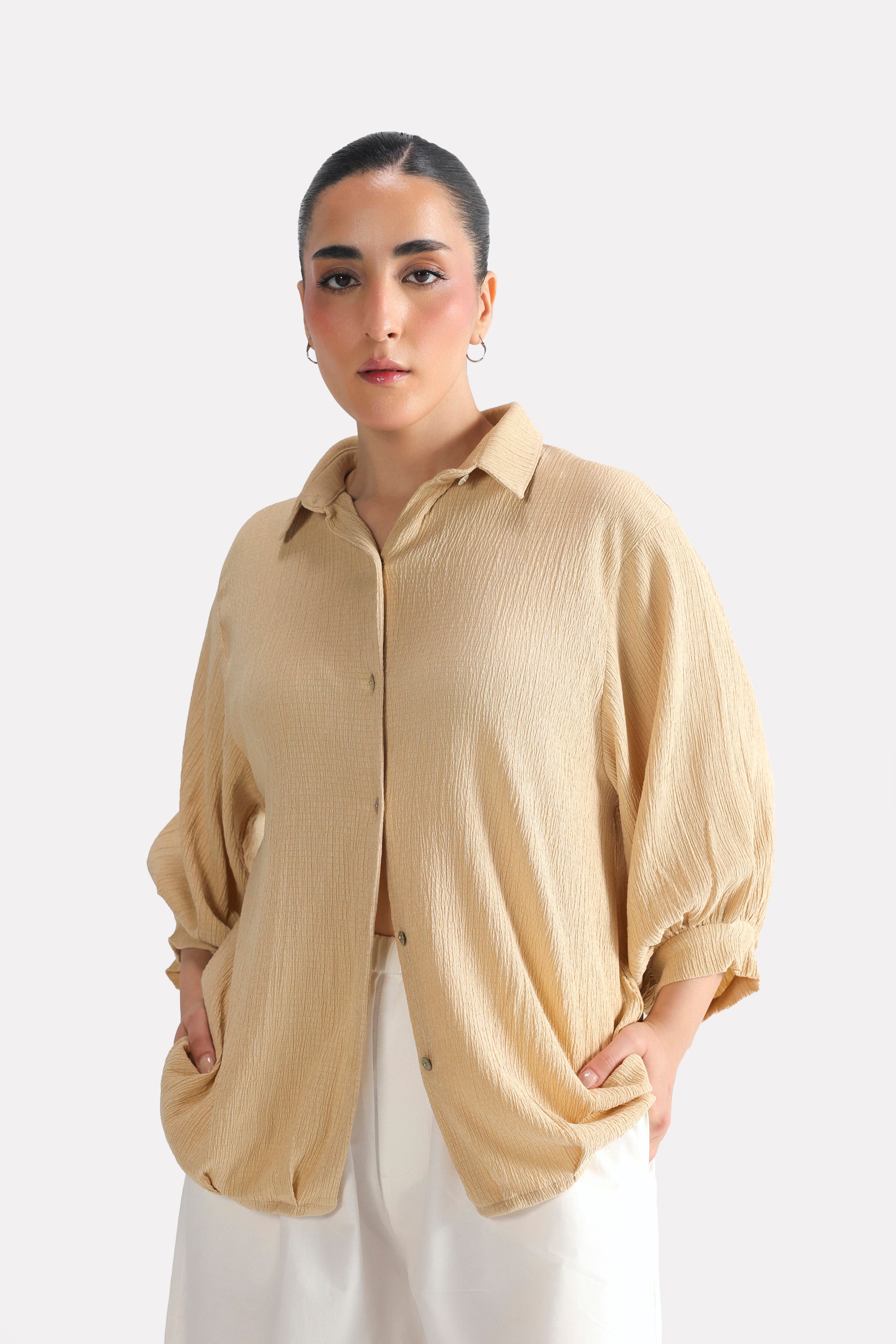 Beige pleated hem woven top in polyester crepe, worn by a model, by SOLA Pakistan.