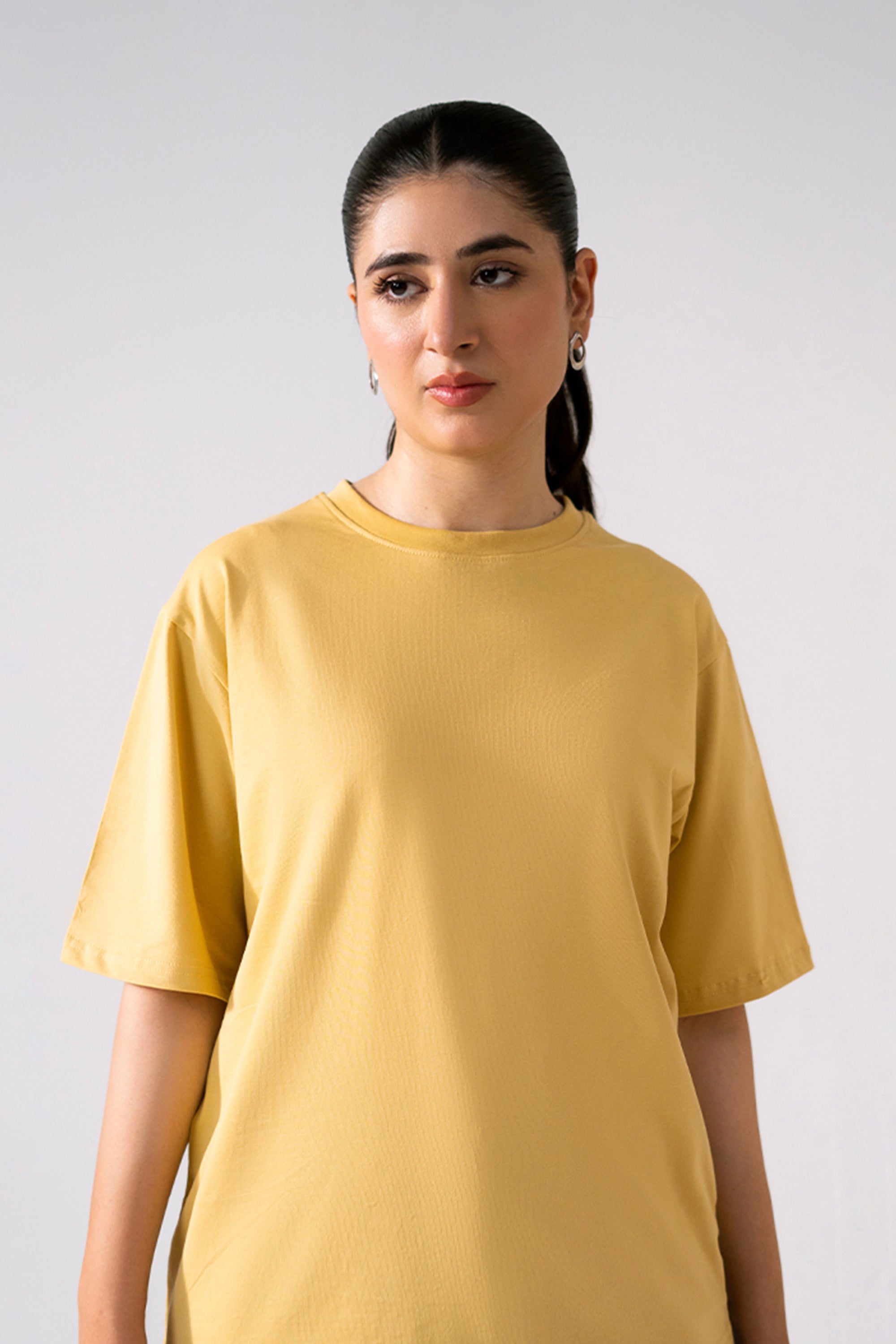 Beige round neck t-shirt in cotton, worn by a model, by SOLA Pakistan.