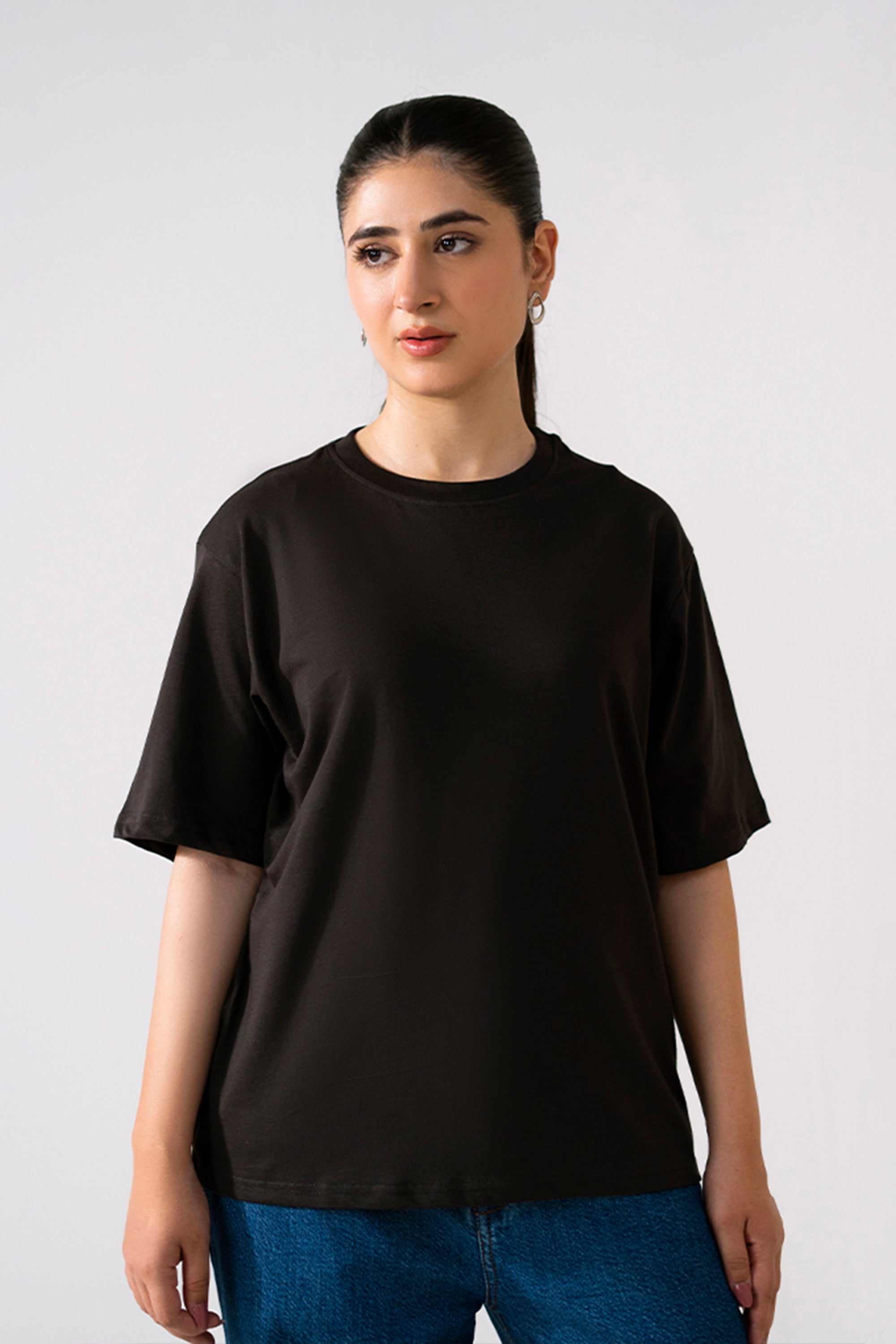 Black round neck t-shirt in cotton, worn by a model, by SOLA Pakistan.