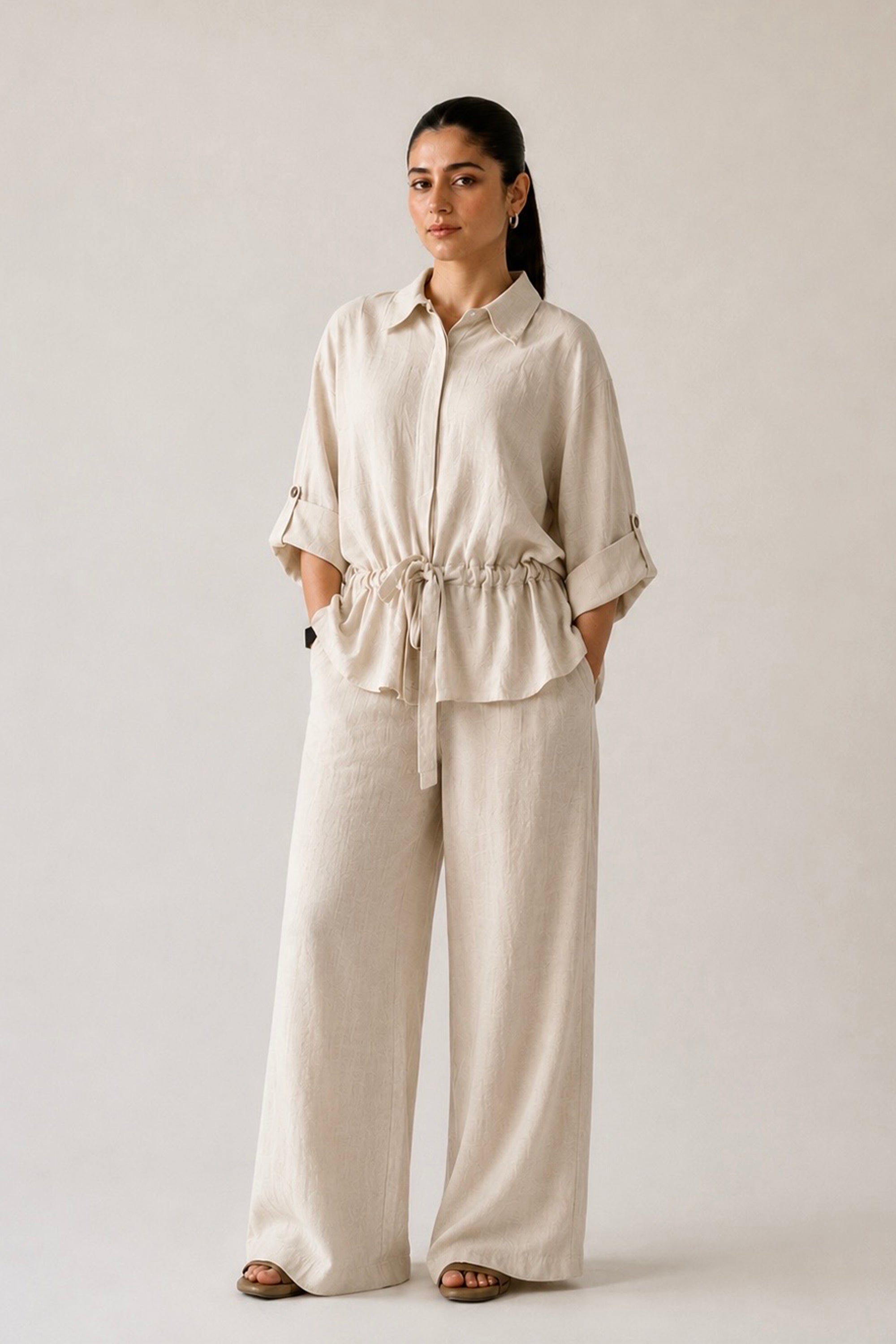 Off white cinched waist bottom in cotton-linen blend, worn by a model, by SOLA Pakistan.