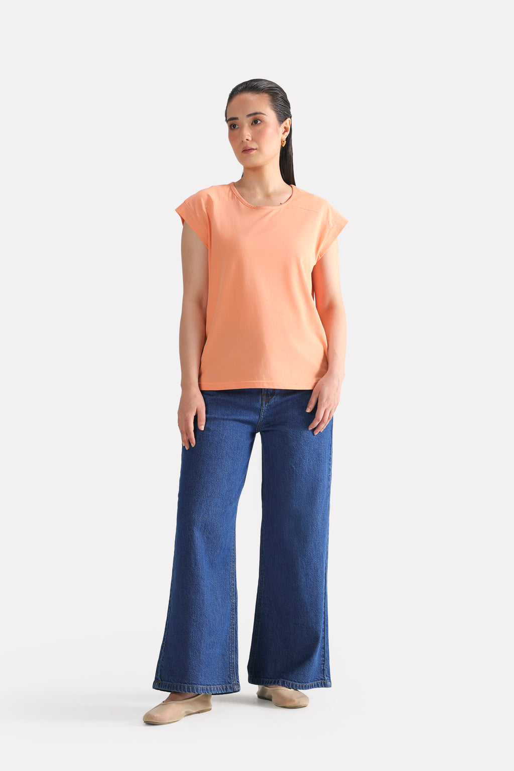Close-up detail on the peach (apricot) relaxed shoulder-tab t-shirt, by SOLA Pakistan.