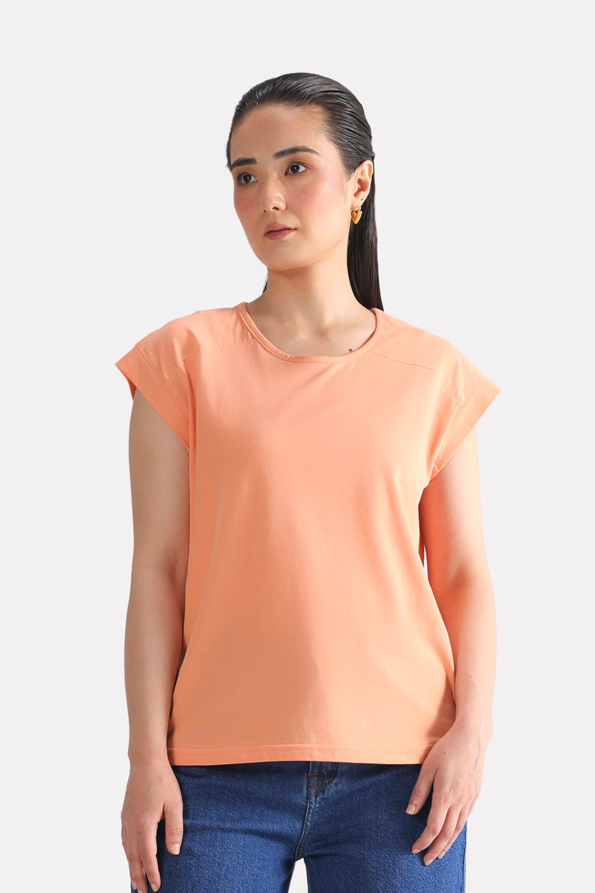 Peach (apricot) relaxed shoulder-tab t-shirt in cotton, worn by a model, by SOLA Pakistan.
