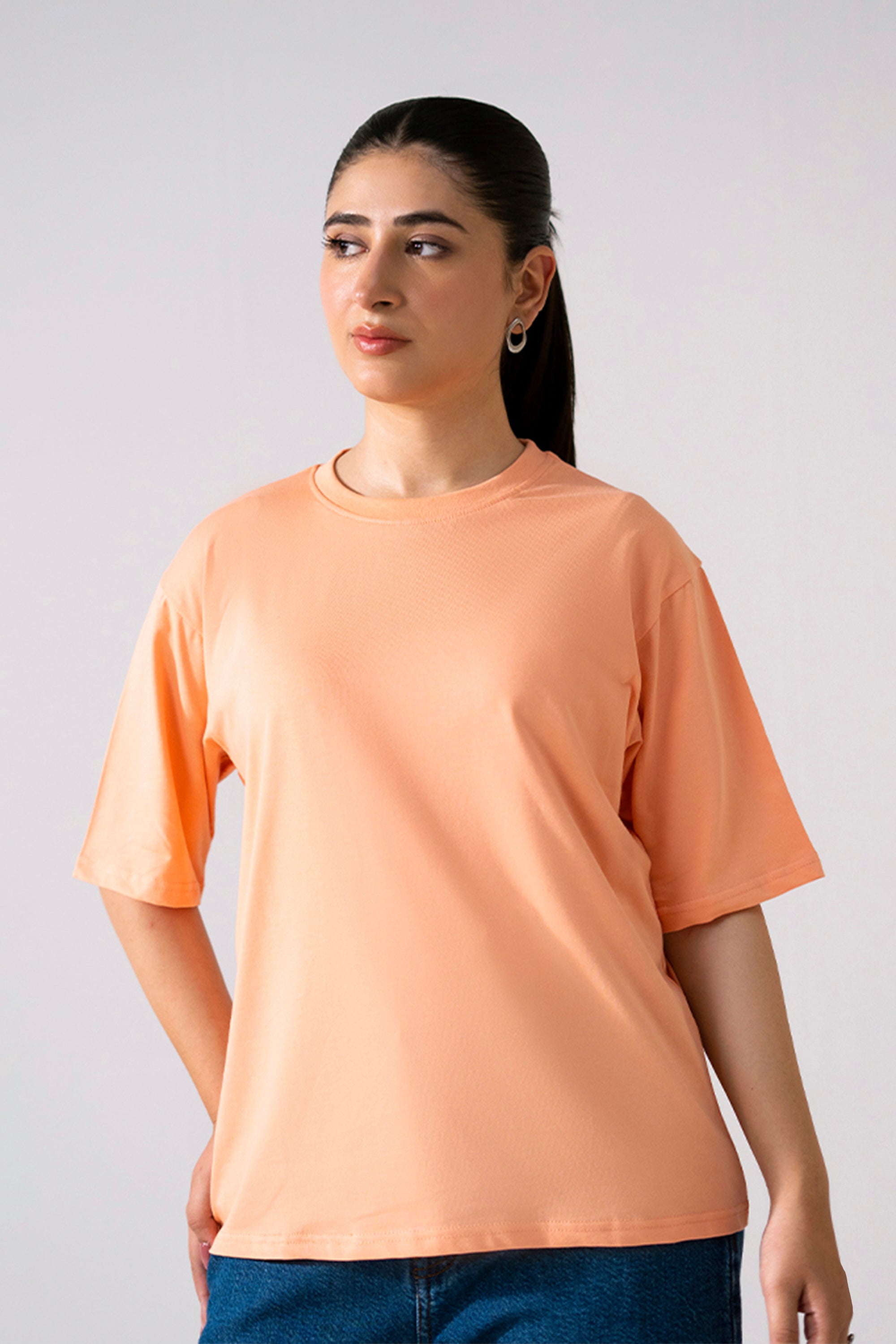 Peach (apricot) round neck t-shirt in cotton, worn by a model, by SOLA Pakistan.